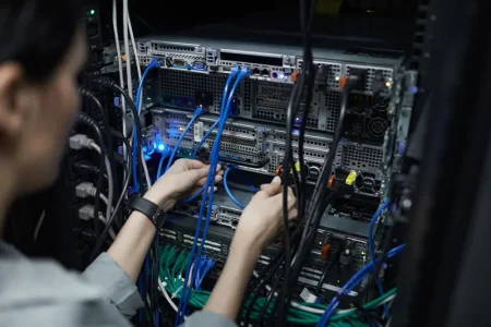 close-up-female-network-technician-connecting-cables-server-cabinet-while-setting-up-supercomputer-data-center-copy-space (1)