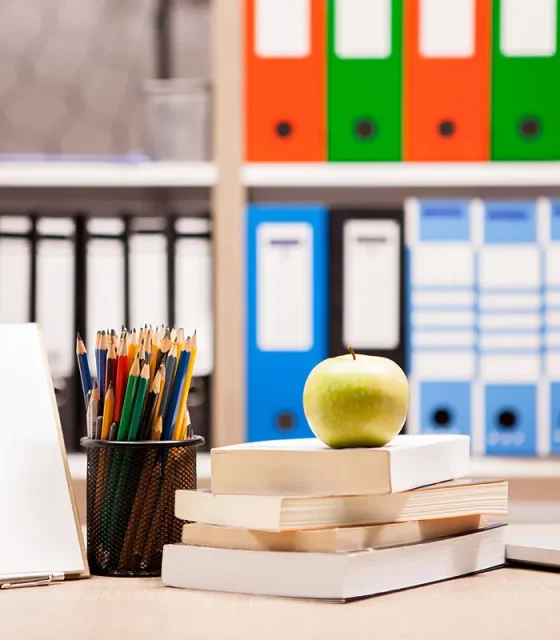 green-apple-pile-books-notebook-pencils-table-with-blurred-white-board-back-school-concept