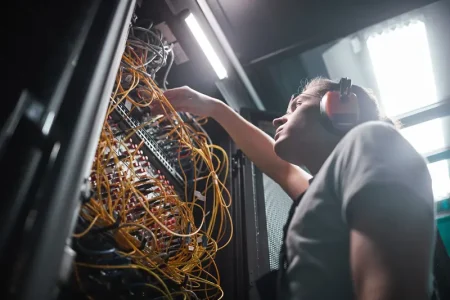 low-angle-portrait-network-engineer-connecting-cables-server-room-during-maintenance-work-data-center-copy-space