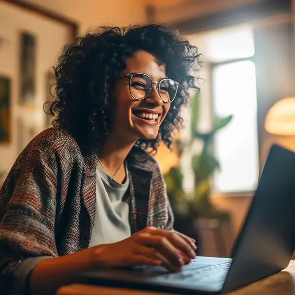 woman-with-curly-hair-is-smiling-smiling-while-using-laptop