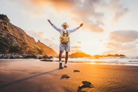 young-man-arms-outstretched-by-sea-sunrise-enjoying-freedom-life-people-travel-wellbeing-concept